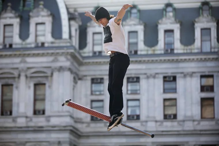 Nic Patino, a professional stunt pogoer, performs a trick at Thomas Paine Plaza, with City Hall in the background.