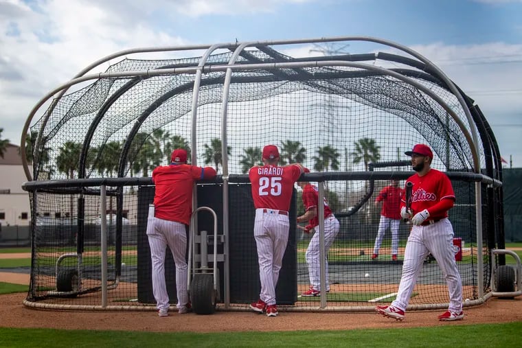 Philadelphia Phillies manager Joe Girardi looks on as players practice in the batting cage during spring training baseball practice in Clearwater, Fla., Monday, Feb. 22, 2021.