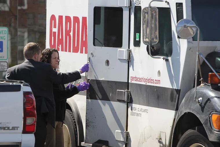 Investigators take a look into an armored car (above) that was robbed outside the TD Bank at 6635 Frankford Ave. in Mayfair (left) yesterday morning. Police said two masked gunmen armed with semiautomatic rifles took an undisclosed amount of cash and fled in a white van. More in Crime Scene on Page 19.