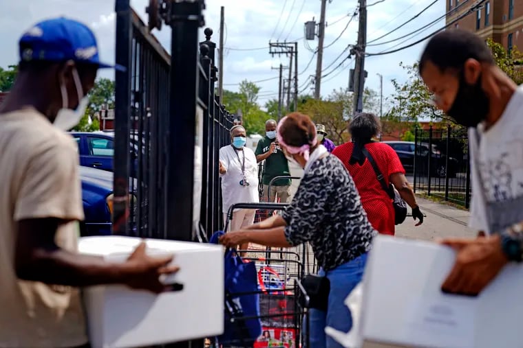 Residents line up at a food distribution site at St. Sabina Catholic Church in the Auburn Gresham neighborhood in Chicago in August. In the neighborhood, many of those working survive paycheck-to-paycheck, and they've suffered, too, amid furloughs and job cuts.