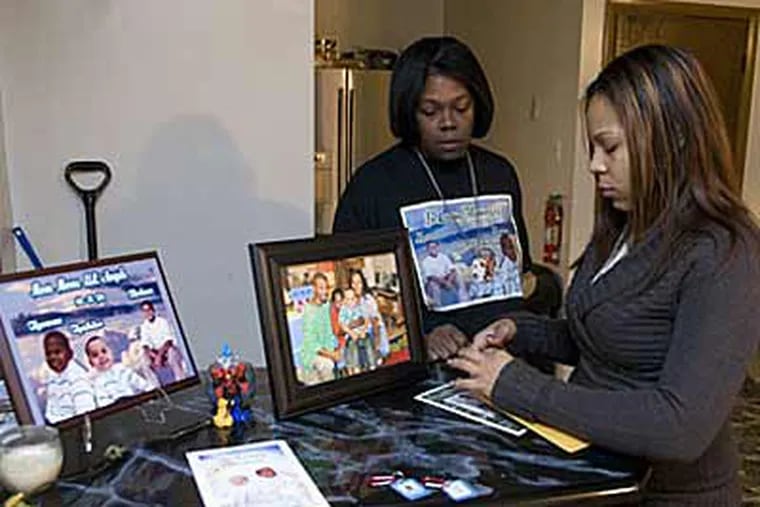Desiree Wylie (left) seen with daughter Jessica eye photos of the three children. "I didn't hear a single on (smoke detector) going off" after fire struck their house on Sept. 21.