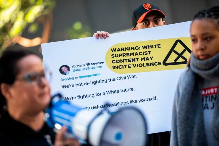 A protester holds a sign with an enlarged tweet while marching with the activist group Change the Terms Reducing Hate Online outside Twitter headquarters in San Francisco on Nov. 19.