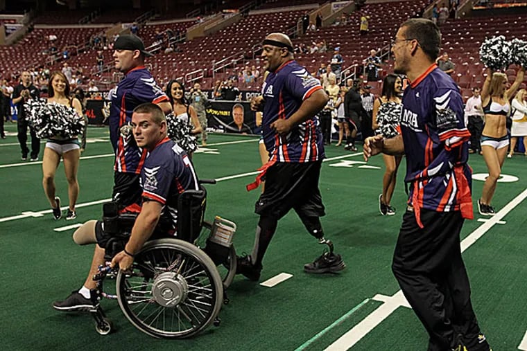 Wounded Warrior Amputee football team members march on the field.