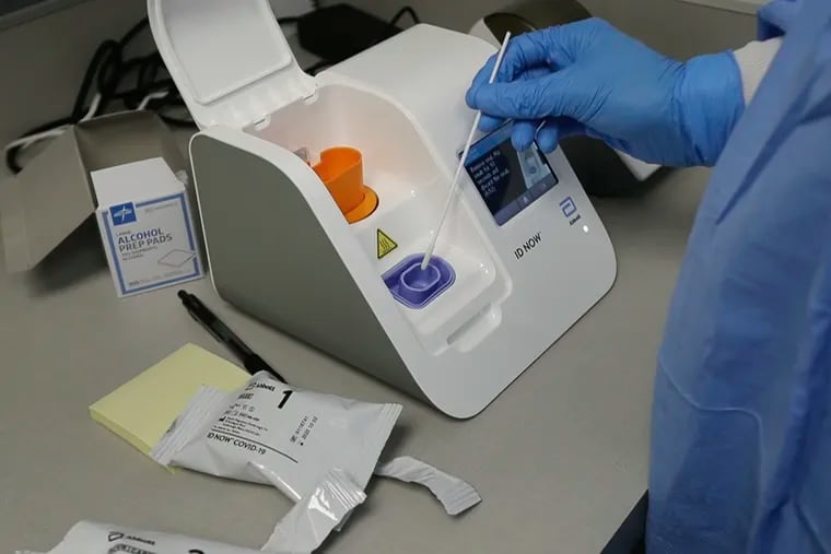 A lab technician in Detroit dips a patient's sample into the Abbott Laboratories ID Now testing machine. The company's cartridge-based coronavirus diagnostic test, government-authorized in March, delivers results within minutes and is being used by the White House.