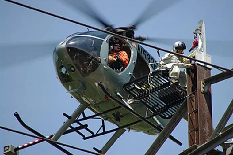 Lineman Carl Pellegrino works on a power line from a platform affixed to a helicopter piloted by Vinnie Carchia. &quot;There haven't been any close calls,&quot; Pellegrino said of their work.