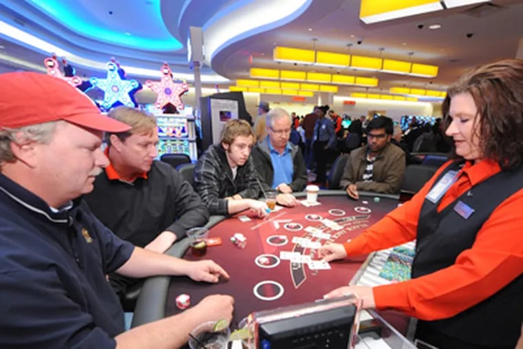 Michael Lee (left), 49, and his buddy Johnny Mac, 47, both from Wayne, play blackjack at a $15 minimum table at the newly opened Valley Forge Casino Resort at the Valley Forge Convention Center in King of Prussia Saturday, March 31. (Clem Murray / Staff Photographer)