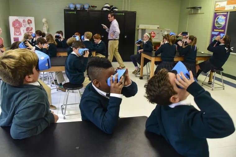 At St. Patrick’s School in Malvern, science teacher Christopher Fender gives a lesson on the Galapagos Islands to a sixth-grade class as they view virtual reality images on Google Expeditions viewers.
