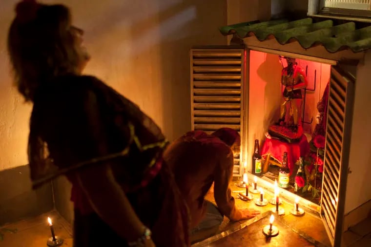 A woman laughs as another lights a candle during the Exuand Pomba Gira ceremony. Many Brazilians view Umbanda as a barely benign version of witchcraft.