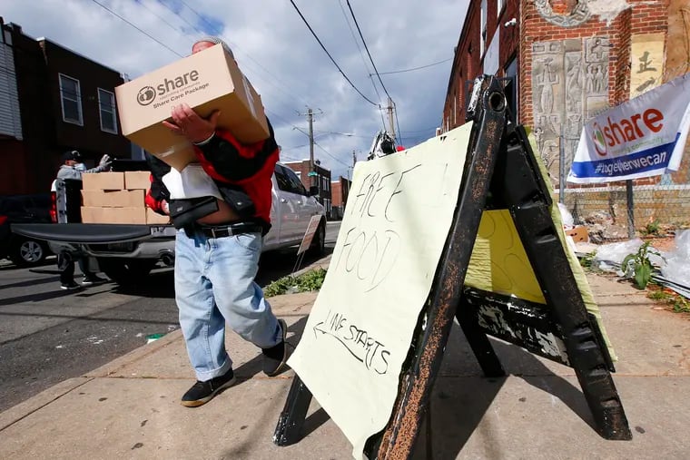 A resident carries his box of food from the Share Food Program distributed at the Young Chances Foundation in the Point Breeze neighborhood of Philadelphia last spring.