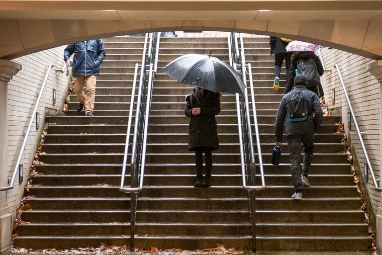 "Marguerite," a student in recovery for cannabis use disorder, conceals her identity with an umbrella while posing in a stairway outside the Penn State libraries on the University Park campus. She is getting support for recovery from her addiction through the Penn State Recovery Community.