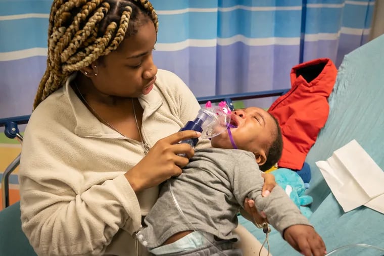 Nazhay Gaffney, and her 8-month-old son, Nasir Hurst, seek treatment for respiratory issues in the emergency department at St. Christopher's Hospital for Children in North Philadelphia in late November. The ER was awash with kids suffering from viruses that triggered asthma attacks. Gaffney was up all night worried about her son's ability to breathe.