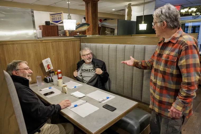 At Hymie's in Merion Station, John Makransky (standing), a patron since he was 6 years old, is joined by fellow R.O.M.E.O. (Retired Old Men Eating Out) Club member Larry Finkelstein (flashing a club shirt) and Brad Sinoff.