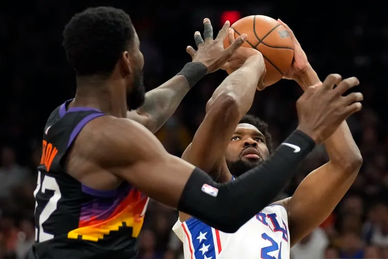Philadelphia 76ers center Joel Embiid (right) shoots over Phoenix Suns center Deandre Ayton during the first half of an NBA basketball game, Sunday, March 27, 2022, in Phoenix.