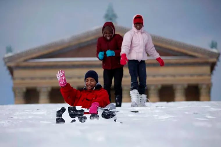 Juanita Streat, left, sleds down the snow-covered steps of the Philadelphia Museum of Art as her daughters, Tayluer Streat, 12, right, and Jazmine Brownlee, 16, look on in the aftermath of a snow storm in Philadelphia.