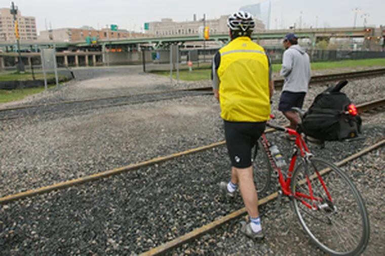 A cyclist and pedestrian take advantage of access to Schuylkill River Park over the CSX tracks at Locust Street. This informal path will become a more structured and safe walkway by the end of 2009.