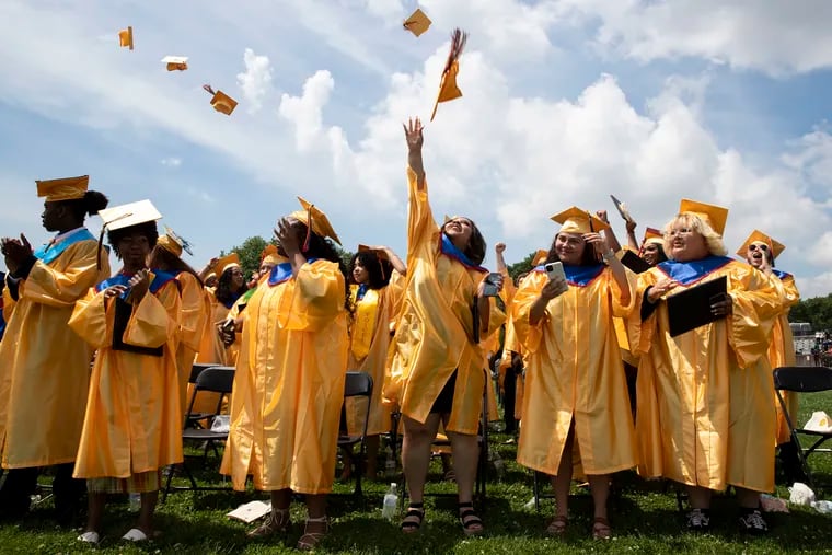 Ashlynn Torres, center, tosses her cap during Frankford High School graduation on Monday.