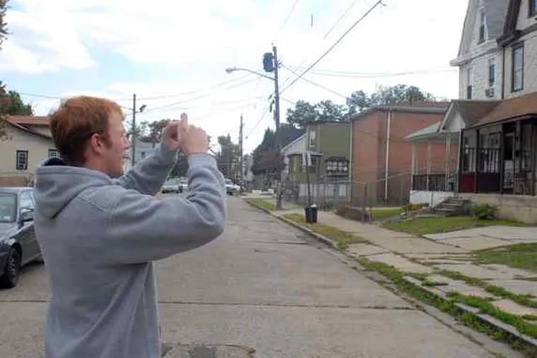 Shawn Murray, a Rowan University student, takes photos in Cramer Hill to be used in a computer model of the neighborhood's storm-water woes.
