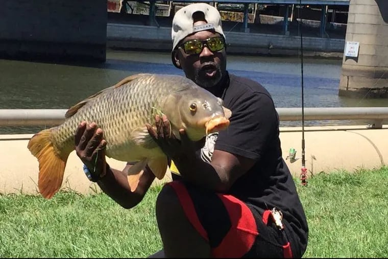 Troy “The Carp Catcher” Rimes, 51, of Germantown, with the 30-pound carp he caught in the Schuylkill River in Center City Sunday.