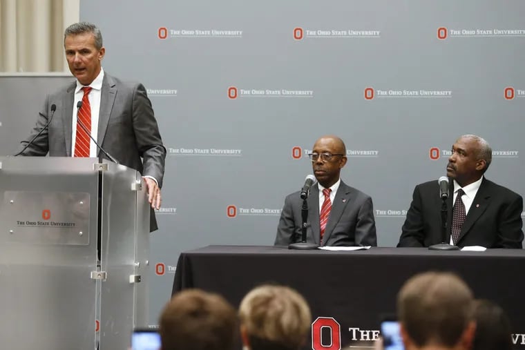 Ohio State football coach Urban Meyer, left, makes a statement during a news conference as university President Michael Drake, center, and athletic director Gene Smith listen in Columbus, Ohio, Wednesday, Aug. 22, 2018.