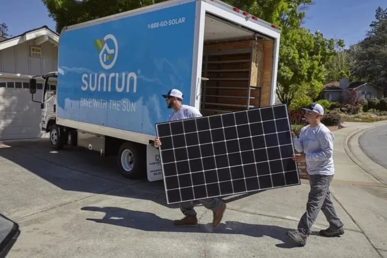 Workers carry a Sunrun solar panel for installation.