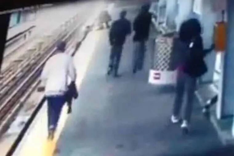 Video grab of baby in stroller that rolled off platform into SEPTA train tracks.  Video shows mother on edge about to jump down.  Notice woman on right hitting the emergency call button before proceeding to give assistance.