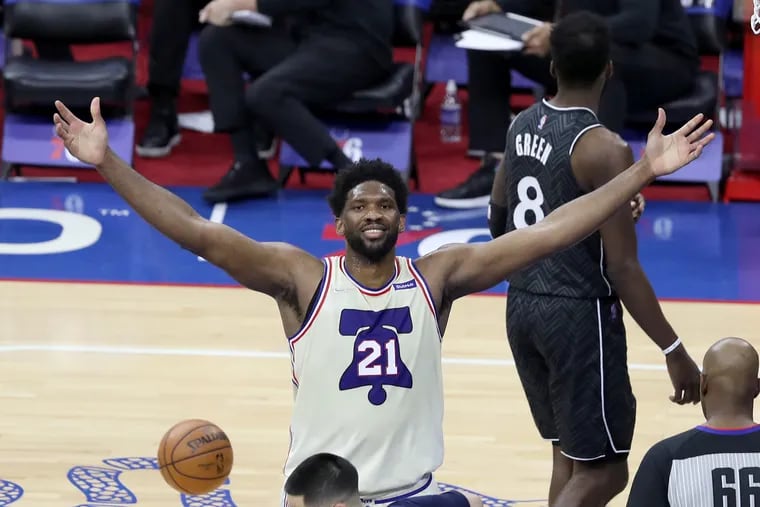 Joel Embiid of the Sixers raises his arms to the crowd after a traditional three-point play against the Nets.