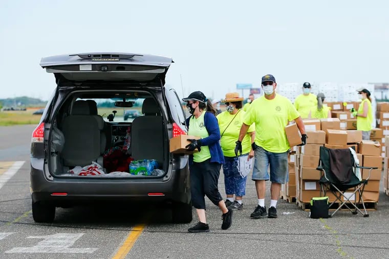 Volunteers carry boxes of food to cars during a food drive for Atlantic City residents and casino workers at Bader Field.