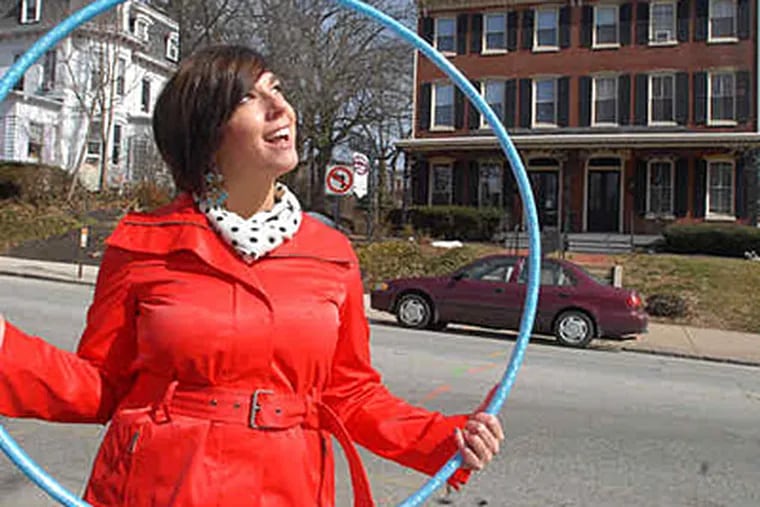 Ashley Ambirge, seen here in downtown West Chester, promotes public hula-hooping on her blog, &quot;The Middle Finger Project,&quot; and is into shaking things up. (Bob Williams / For the Inquirer)