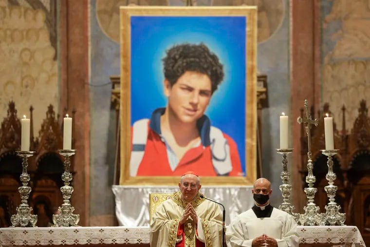 An image of 15-year-old Carlo Acutis, an Italian boy who died in 2006 of leukemia, is seen during his beatification ceremony celebrated by Cardinal Agostino Vallini, center, in the St. Francis Basilica, in Assisi, Italy.