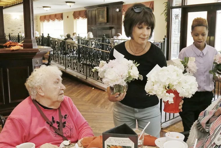 Leona Davis (center) delivers flowers to residents at the Spring Hills Assisted Senior Living Facility in Cherry Hill on Sunday. Davis founded Forget Me Know Flowers, a Haddonfield-based nonprofit that transforms wedding flowers into "bedside bouquets"  for residents of nursing homes and hospitals. ELIZABETH ROBERTSON / Staff Photographer 