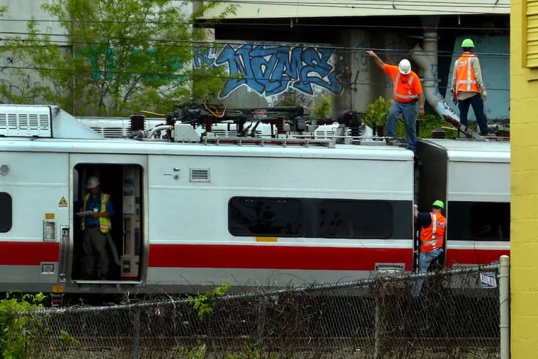 Metro-North Railroad employees work at the scene of the train derailment and crash in Bridgeport, Conn.