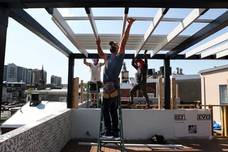 (left to right) Glenn Perlman, David Posternack, and Isabel Hernandez work on the pergola of a roof deck in the Spring Garden neighborhood of Philadelphia, Pa. on Tuesday, September 8, 2020. Posternack said that he's seen an increase in business as people look for more outdoor living space during the pandemic.