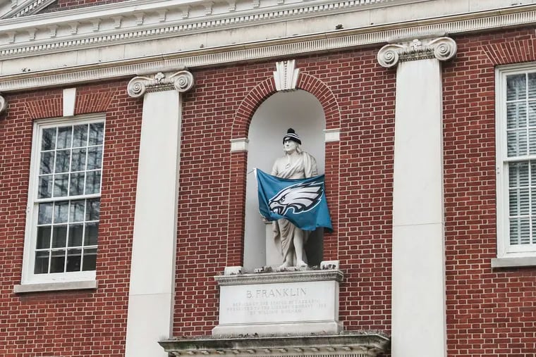 An Eagles flag and hat adorn the Ben Franklin statue at Library Hall in Old City on Tuesday, Feb. 7, 2023.