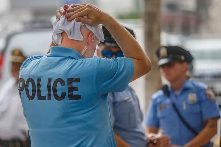 Philadelphia Police Officer Philip Stahl uses a cold wet towel on his shaved head to try to cool while on duty, monitoring a protest at 8th and Cherry Streets on July 3, 2018.