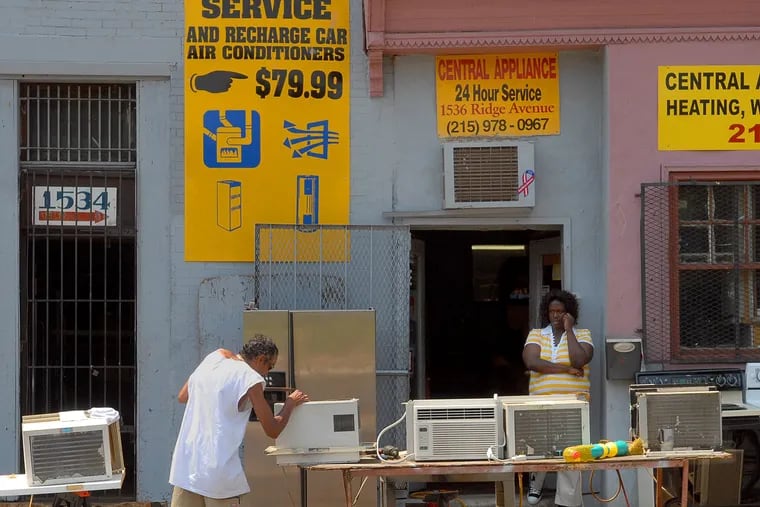 A technician fixes an air conditioner in front of Central Appliance on Ridge Avenue in 2008.