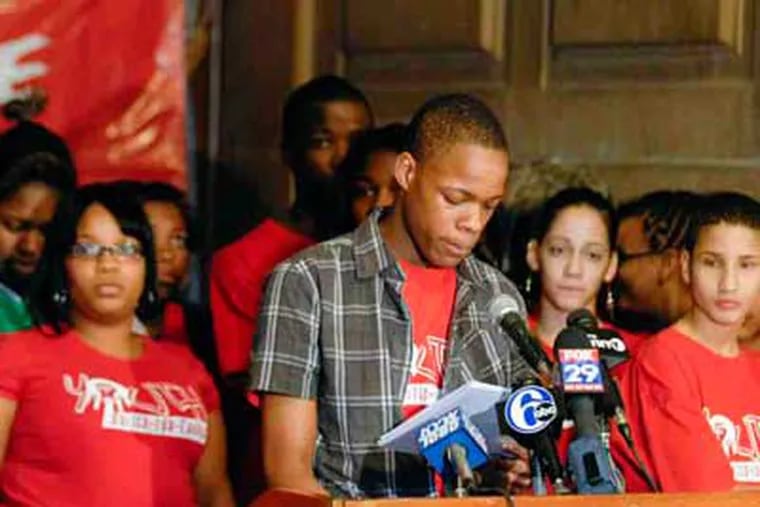 Brandon Johnson, a Youth United for Change member, reads from a report critical of the school district's zero-tolerance approach to discipline, during a press conference at City Hall yesterday. (Ron Tarver / Staff)
