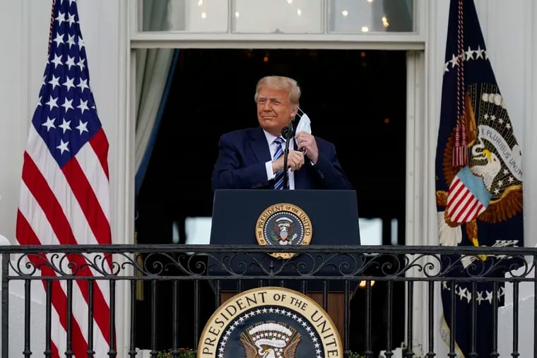 President Donald Trump removes his face mask to speak from the Blue Room Balcony of the White House to a crowd of supporters on Saturday.