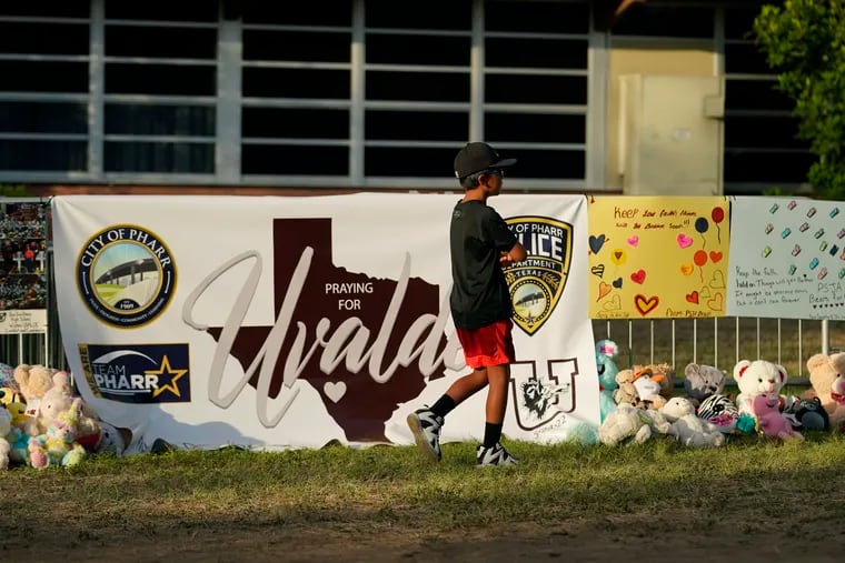 A boy walks along a memorial outside Robb Elementary School created to honor the victims killed in last week's school shooting, Friday, June 3, 2022, in Uvalde, Texas.