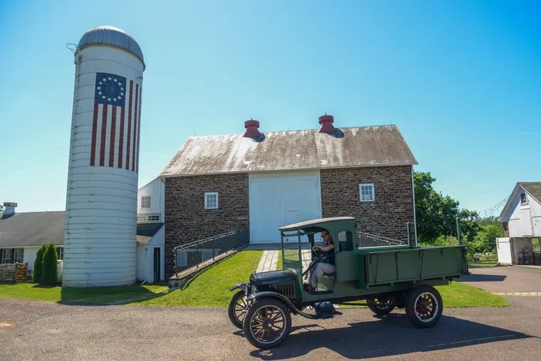 Kevin Roberts drives an antique truck in front of the barn at Durham Hill Farm, where his family runs a wedding event business.