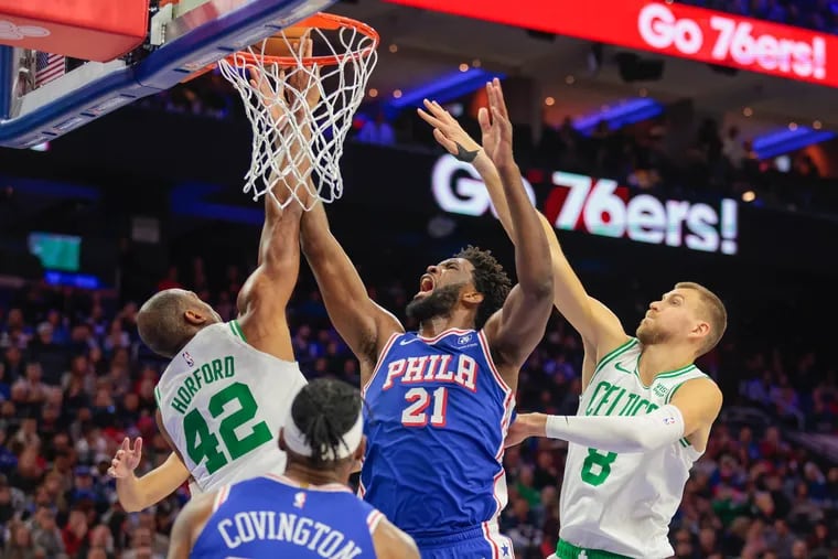 Joel Embiid gets fouled as he goes up for a shot between Boston Celtics center Al Horford (left) and center Kristaps Porzingis during the second quarter.