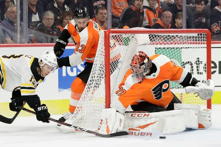 Flyers goaltender Carter Hart stopping Bruins center Charlie Coyle's overtime shot with Flyers center Kevin Hayes watching on Monday.