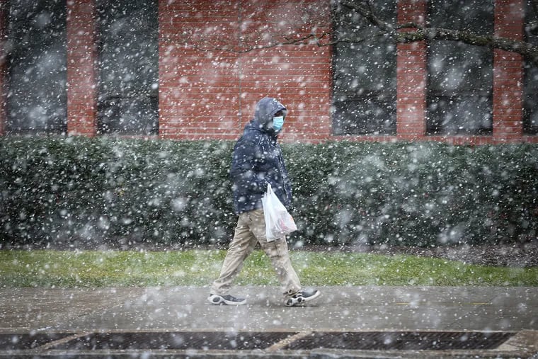A pedestrian navigates Market Street near 34th Street as a snow squall storm moves through Philly on Wednesday.