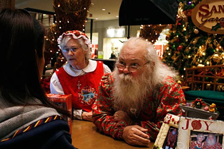 Santa A. Claus and Mrs. Claus with a customer in the Jersey Gardens Mall in Elizabeth, N.J. Their layoff from cost-cutting Concord Mall in Wilmington left their seasonal patrons bereft. (Ashlee Espinal / Staff Photographer)