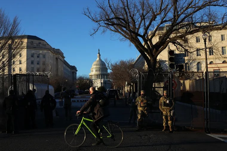 National Guard members stand behind a fence outside the U.S. Capitol on the day before the presidential inauguration of Joe Biden in Washington, D.C., on Tuesday, Jan. 19, 2021.