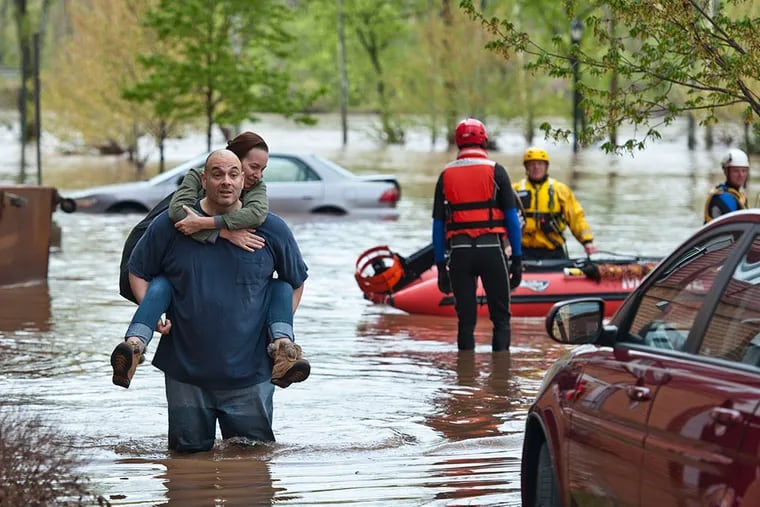 Rene Rivera carries his wife, Melissa Hotsko, from their building at the Riverview Landing Apartments in Eagleville, West Norriton, after the rising Schuylkill flooded garage and first floor units. He decided not to wait for rescue boats to arrive.
