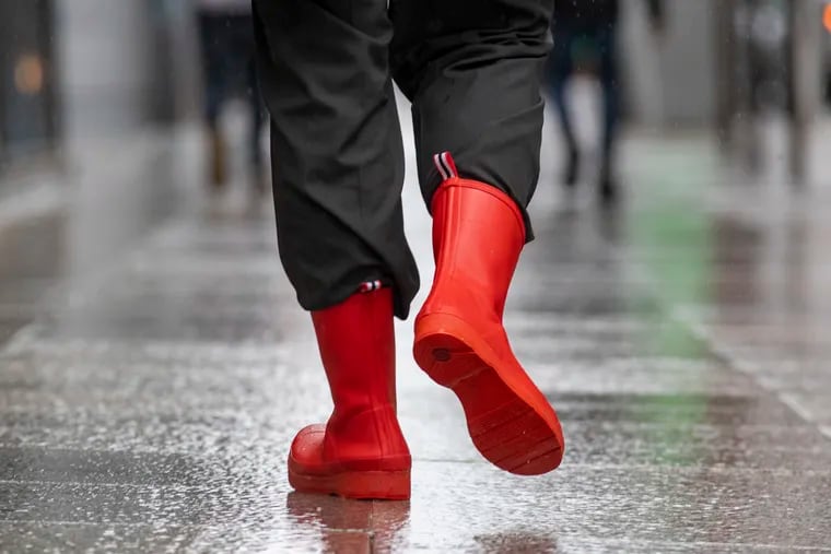 Red rain boots walking west on Market Street on on a rainy day.