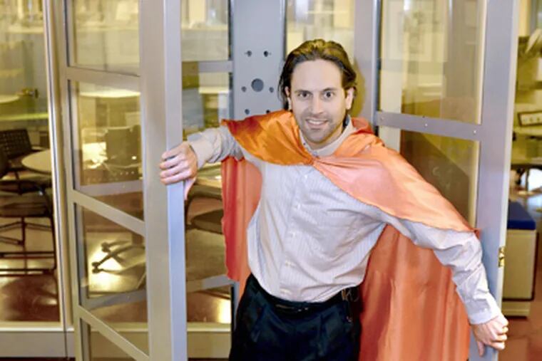 In a cape he often dons at presentations, Dave Girgenti emerges from a phone booth at his offices. Charities are vying for a big prize. (Tom Gralish / Staff Photographer)