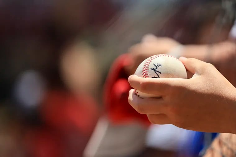 A fan holds an autographed baseball.