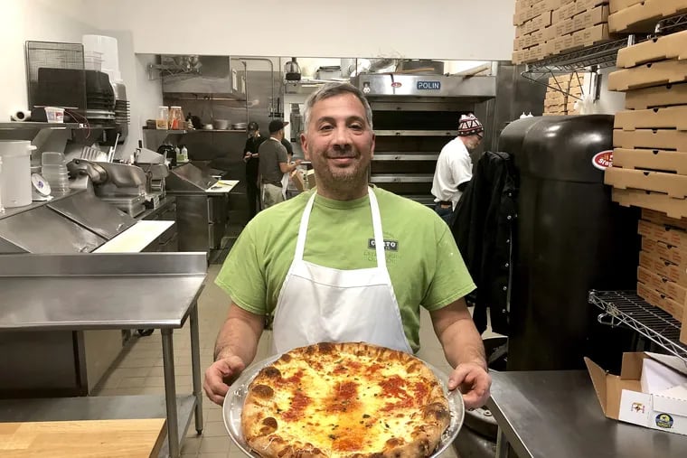 Danny DiGiampietro with an "upside-down" pizza (cheese on the bottom, sauce on top) at Angelo's Pizza in South Philadelphia.