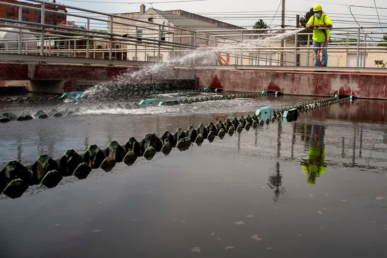 Mo Keys hoses down the weirs of a sewage settlement tank at the Borough of Conshohocken Authority wastewater treatment plant on East Elm Street. The borough council was considering selling the sewer system, but decided to retain it after public opposition mounted.